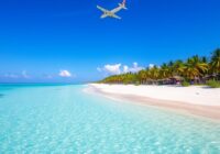 Flugzeug fliegt über einen tropischen Strand